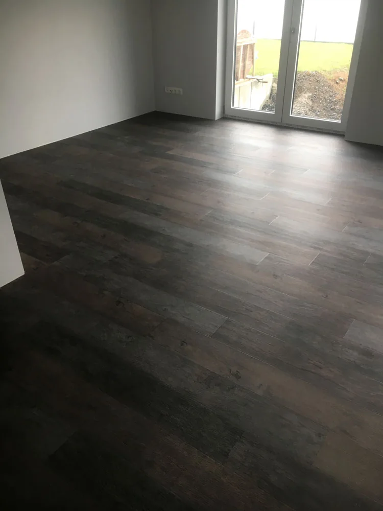 Dunkler Bodenbelag in einem Raum mit bodentiefem Fenster