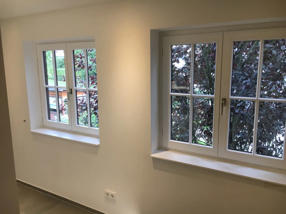 Weiße Holzfenster mit Sprossen in einem hellen Raum