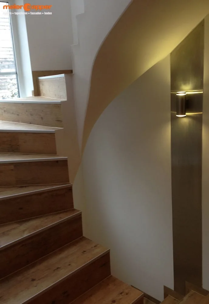 Treppe mit Holzstufen neben einer gestalteten Wandnische